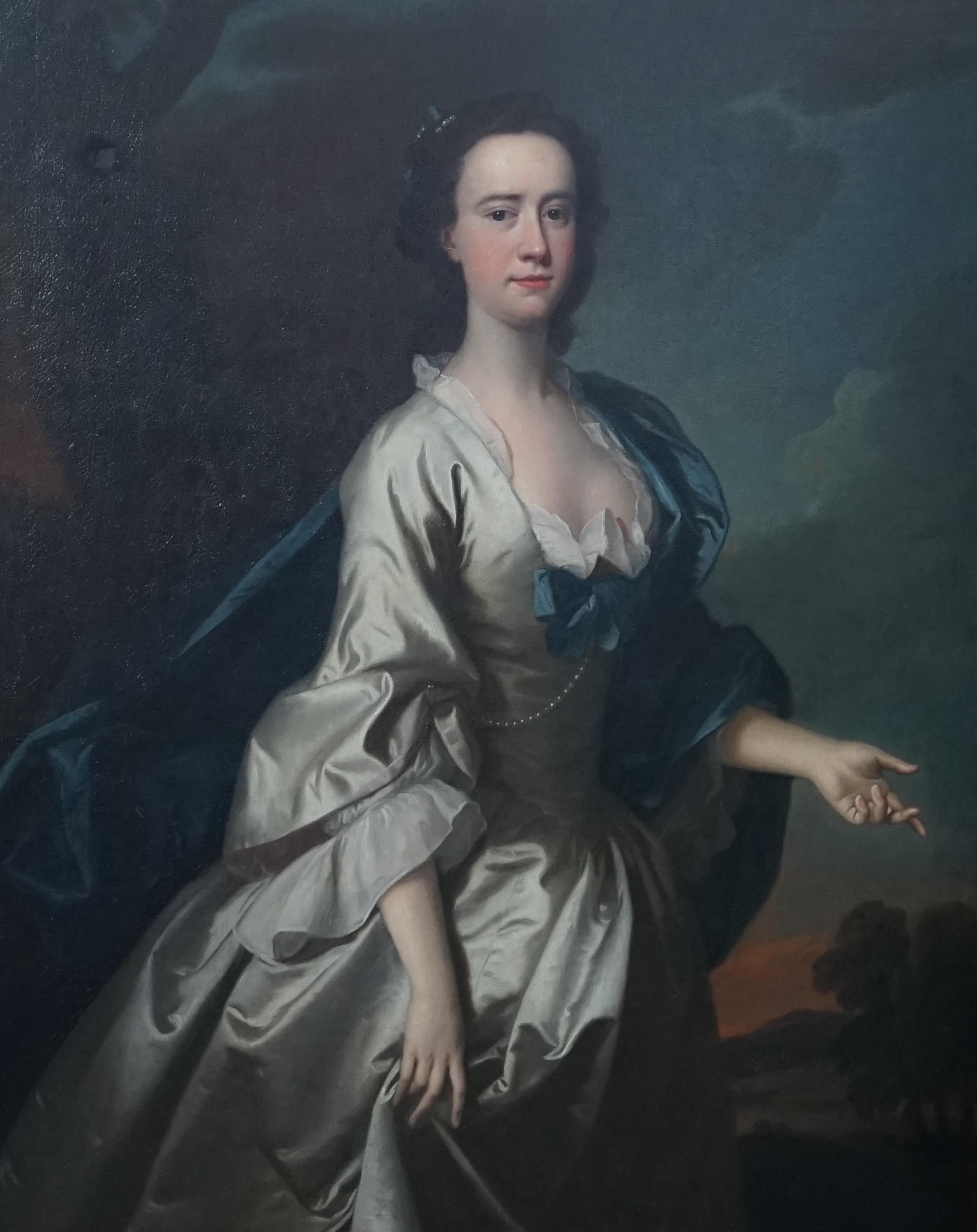 Thomas Hudson (British, 1701-1779), Portrait of a lady standing three quarter length in a landscape, wearing a grey dress and blue shawl, oil on canvas, 128 x 102cm